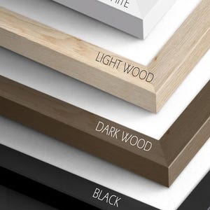 May include: Close-up of framed prints with four different frame colors: white, light wood, dark wood, and black. The text on the image reads "WHITE", "LIGHT WOOD", "DARK WOOD", "BLACK", and "FRAMED PRINTS".