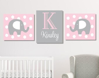 May include: A set of three wall art pieces. Two pink square canvases with white polka dots and a gray elephant silhouette. The center canvas is gray with a pink letter "K" and the name "Kinsley" in script.