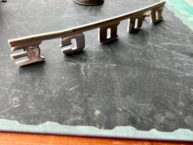 May include: A silver metal key-shaped emblem with the word "FORD" embossed on it.