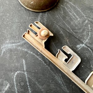 May include: A silver metal car emblem with the word "Dodge" embossed on it. The emblem has a screw hole on the back.