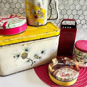 Distressed 6 Piece Farmhouse Kitchen Tin Lot, Decoware Pinecone Breadbox, Butter Mint Tins, Flour Sifter, Cheese Shredder & Red Placemat