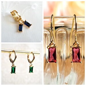 Könnte beinhalten: Drei Paar goldene Ohrringe mit verschiedenen Edelsteinen. Das erste Paar hat blaue Edelsteine, das zweite Paar hat grüne Edelsteine und das dritte Paar hat rote Edelsteine.