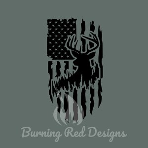 May include: Black and white silhouette of a deer with antlers standing in front of a distressed American flag. The flag is tattered and worn, with a black and white flame design at the bottom. The text "Burning Red Designs" is at the bottom of the image.