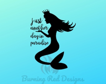May include: Black silhouette of a mermaid wearing a crown, with long flowing hair and a fishtail, set against a gradient blue background. The text "just another day in paradise" is written in cursive. The Burning Red Designs logo is at the bottom.