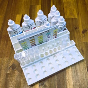 May include: A white plastic test kit organizer with multiple test tubes and bottles of liquid test solutions. The kit includes tests for pH, ammonia, nitrite, high range pH, and freshwater master test kit.