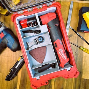 以下が含まれることがあります： 赤色のツールボックスには、赤と黒のMilwaukee FUELマルチツール、バッテリー、サンディングパッドなど、さまざまな電動工具とアクセサリーが収納されています。 その他のツールには、青と黒のジグソー、黄色の巻尺、カッターナイフが含まれています。