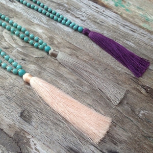 May include: Three turquoise beaded necklaces with tassels. The tassels are peach, gray, and purple.