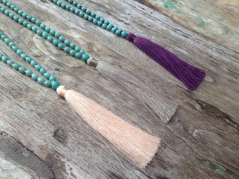 May include: Three turquoise beaded necklaces with tassels. The tassels are peach, gray, and purple.