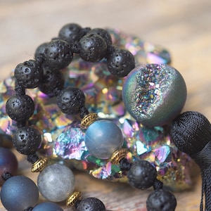 May include: A black lava rock and blue agate beaded necklace with a black tassel and a iridescent crystal bead.