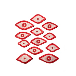 May include: A collection of 12 red felt eye patches with white embroidered pupils. The patches are arranged in a staggered pattern, resembling a pyramid.