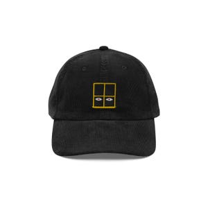 May include: Black corduroy baseball cap with a gold embroidered window with two eyes inside.
