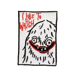 Puede incluir: Parche blanco bordado con contornos negros de un monstruo de dibujos animados con ojos y boca rojos. El texto "Me gusta ver" está escrito en rojo sobre el monstruo.