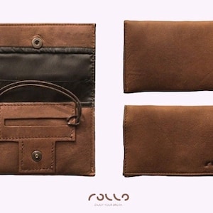 May include: A brown leather tobacco pouch with a flap that opens to reveal a black fabric interior. The pouch has a small pocket for rolling papers and a snap closure. The pouch is made by Rollo.