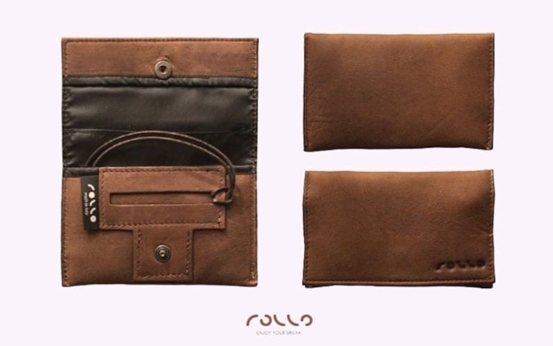 May include: A brown leather tobacco pouch with a flap that opens to reveal a black fabric interior. The pouch has a small pocket for rolling papers and a snap closure. The pouch is made by Rollo.