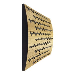 Puede incluir: Panel de pared de madera curvado. El panel es de madera clara con detalles horizontales de color gris oscuro. El panel tiene un borde negro en el lado izquierdo. Mide aproximadamente 100 cm de largo.