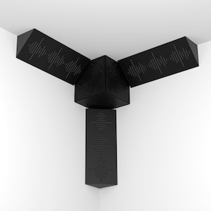 Puede incluir: Un difusor de sonido geométrico negro diseñado para esquinas. Cuenta con tres secciones anguladas con patrones de ondas de sonido y un cubo central. La sección inferior es un panel vertical con un diseño de ondas de sonido similar.