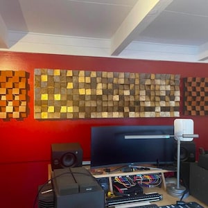 May include: Three rectangular wall-mounted acoustic panels composed of numerous small, square wooden blocks of varying depths. The central panel features a mix of natural wood tones and metallic gold leaf accents, while the side panels are brown.