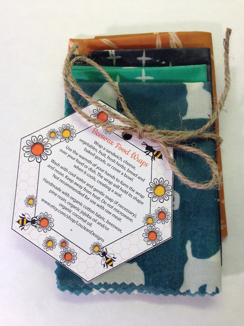 Peut inclure: Un ensemble de quatre emballages alimentaires en cire d'abeille avec des motifs diff&eacute;rents. Les emballages sont li&eacute;s ensemble avec de la ficelle et une &eacute;tiquette qui indique "Beeswax Food Wraps" et comprend des instructions d'utilisation. L'&eacute;tiquette comprend &eacute;galement l'adresse du site Web www.etsy.com/shop/LouJeanDesigns.