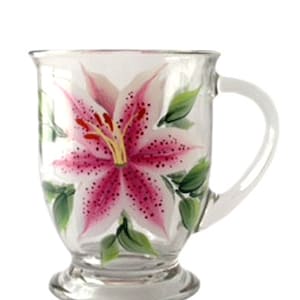 May include: A clear glass mug with a hand-painted pink and white lily flower design.