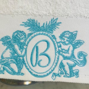 Up close look at a embroidery design featuring two cherub angels and a monogram letter B