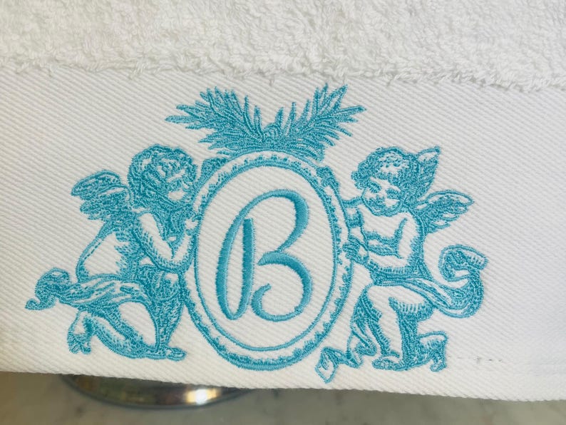 Up close look at a embroidery design featuring two cherub angels and a monogram letter B