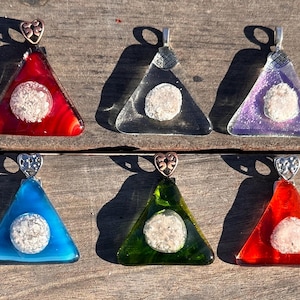 May include: Six triangular glass pendants with a heart-shaped bail. Each pendant has a white, round, textured piece of glass inside. The pendants are in the colors red, clear, purple, blue, green, and red.