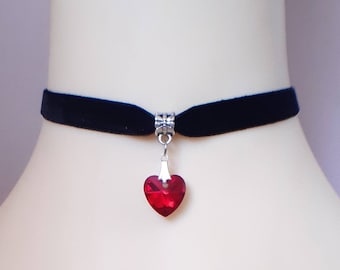 May include: A black velvet choker necklace with a silver heart pendant featuring a red crystal.