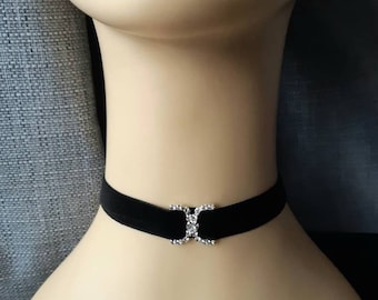 May include: A black velvet choker with a silver and rhinestone X-shaped clasp.