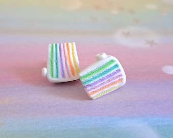 Könnte beinhalten: Zwei Regenbogen-Schichtkuchen-Ohrringe aus Polymer Clay. Die Ohrringe sind weiß mit regenbogenfarbenen Schichten aus Zuckerguss.