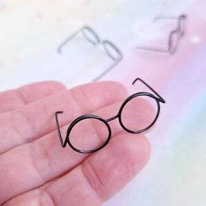 May include: A pair of black round wire-framed glasses with a thin wire frame.