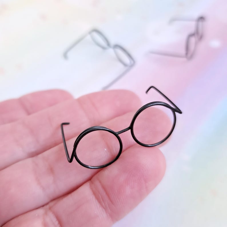 May include: A pair of black round wire-framed glasses with a thin wire frame.