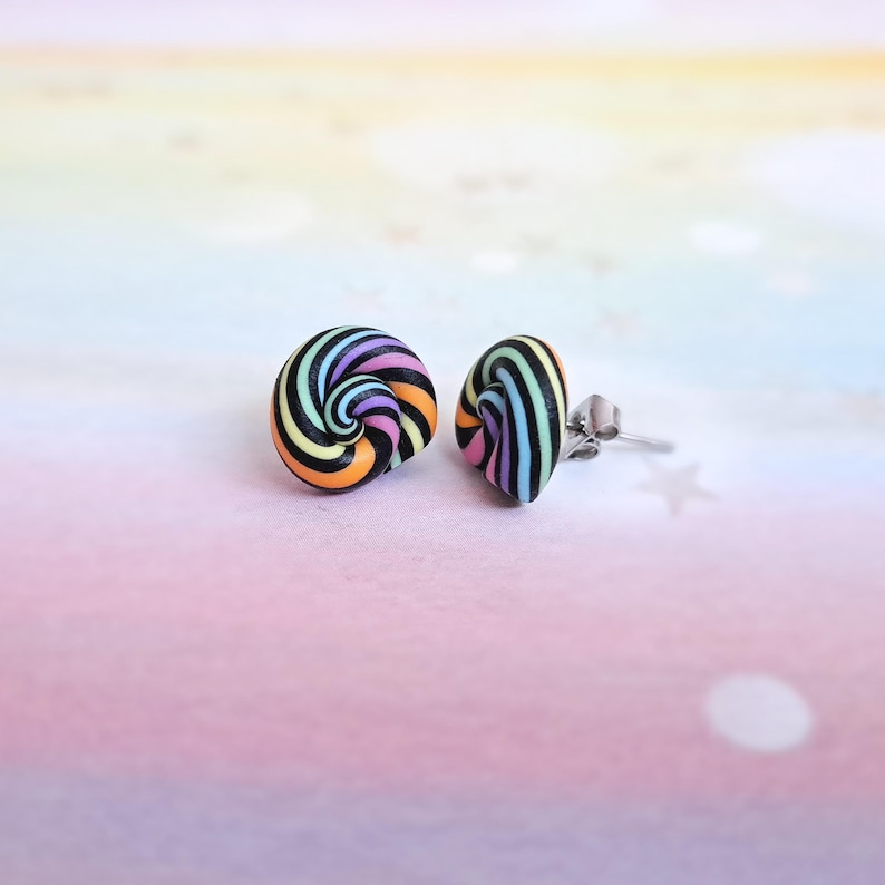 K&ouml;nnte beinhalten: Ein Paar bunte Wirbel-Ohrstecker mit schwarzen Streifen. Die Ohrringe sind aus Polymer Clay gefertigt und haben einen silbernen Stift.