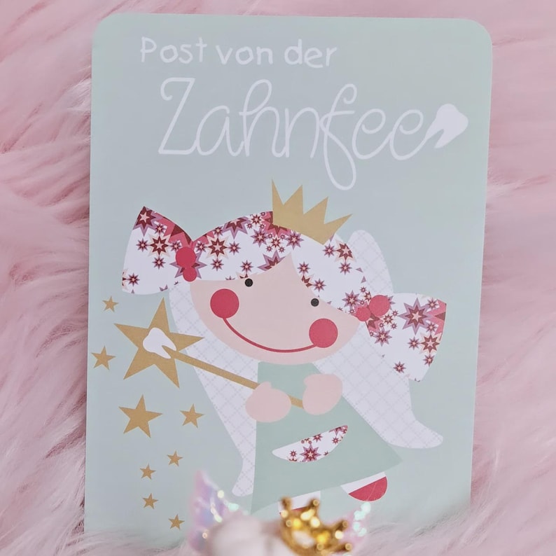 May include: A rectangular light green card featuring the text Post von der Zahnfee and a graphic of a fairy with a gold crown, pink cheeks, and a star-tipped wand. The fairy has hair decorated with red and white star patterns and wears a green dress.