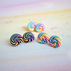 K&ouml;nnte beinhalten: Ein Set mit sechs bunten Wirbelohrringen. Die Ohrringe sind aus Polymer Clay gefertigt und haben ein Regenbogenwirbelmuster. Es gibt zwei Paare Regenbogenwirbelohrringe und ein Paar schwarze und Regenbogenwirbelohrringe.