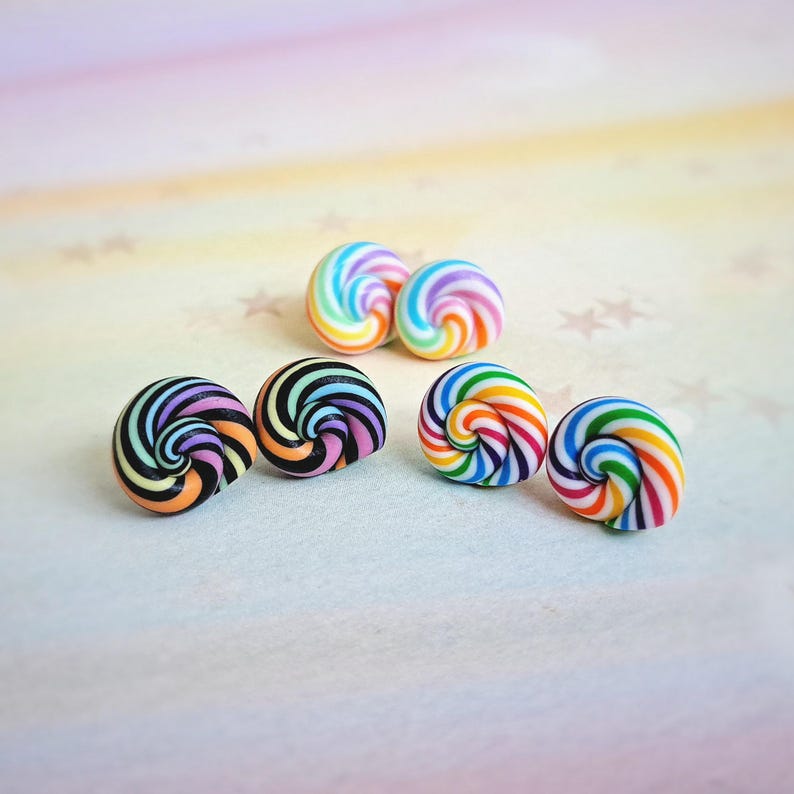 K&ouml;nnte beinhalten: Ein Set mit sechs bunten Wirbelohrringen. Die Ohrringe sind aus Polymer Clay gefertigt und haben ein Regenbogenwirbelmuster. Es gibt zwei Paare Regenbogenwirbelohrringe und ein Paar schwarze und Regenbogenwirbelohrringe.