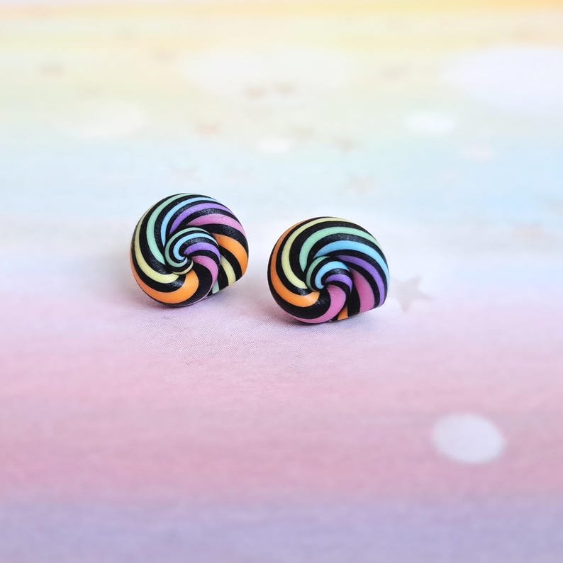K&ouml;nnte beinhalten: Ein Paar bunte Wirbelohrringe. Die Ohrringe sind aus Polymer Clay gefertigt und haben ein schwarzes und regenbogenfarbenes Wirbeldesign.