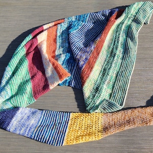 May include: A colorful striped crochet scarf with a variety of colors including green, blue, red, and yellow.