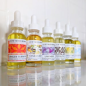 May include: Eight small glass bottles with dropper tops filled with a clear yellow liquid. Each bottle has a label with a different floral design and the text "Leaf Seed Berry" and "Naturally Effective Skin Care". The labels also list the scent of each bottle, including Ginger Turmeric, Vanilla Bean, Lavender, Frankincense, Sweet Meadow, and Chamomile.