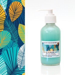 May include: A blue bottle of Blue Tansy Milk Jelly Cleanser by Leaf Seed Berry, a naturally effective skin care brand. The bottle has a white pump top and a label with a tropical leaf design.