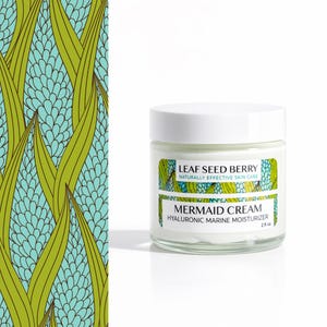 May include: A glass jar of "Mermaid Cream" hyaluronic marine moisturizer with a white lid. The label reads "Leaf Seed Berry, Naturally Effective Skin Care." The jar is 2 fl oz. A patterned design of green leaves and blue floral shapes is on the left.