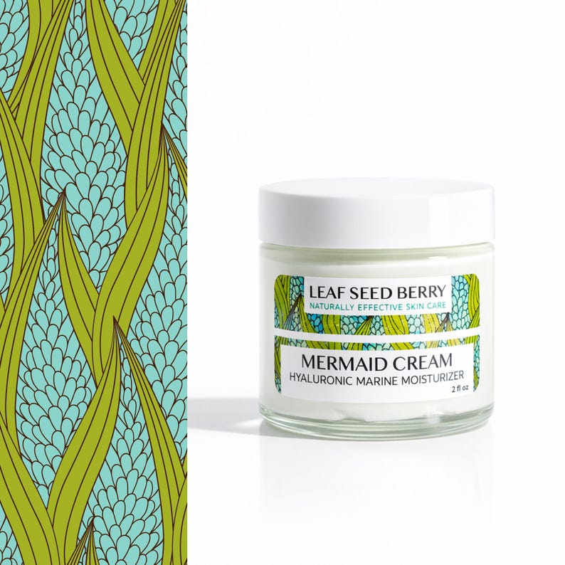 May include: A glass jar of "Mermaid Cream" hyaluronic marine moisturizer with a white lid. The label reads "Leaf Seed Berry, Naturally Effective Skin Care." The jar is 2 fl oz. A patterned design of green leaves and blue floral shapes is on the left.