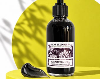 Może przedstawiać: Przezroczysta butelka z czarnym żelem do mycia twarzy z węglem aktywnym i czarną pompką. Etykieta zawiera napis LEAF SEED BERRY, CHARCOAL GEL, FACE CLEANSER WITH TEA TREE oraz 4 fl. oz. Obok butelki znajduje się kropla czarnego żelu.