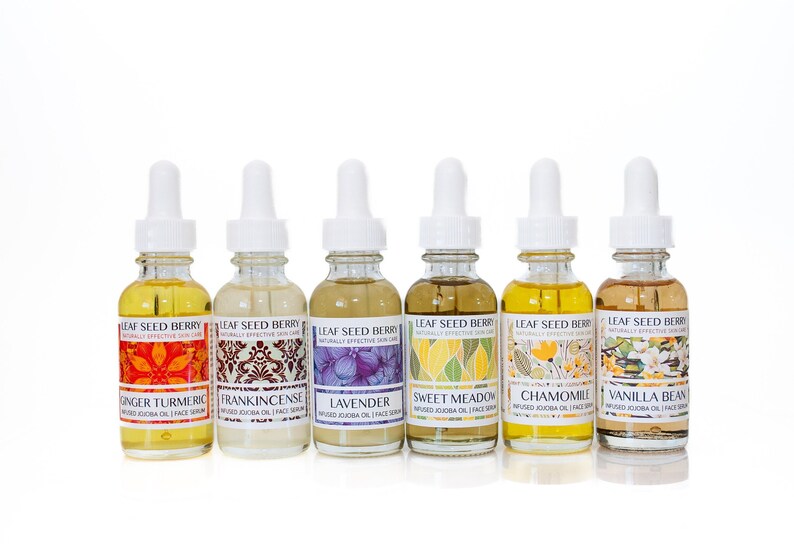 May include: Seven glass bottles with white dropper tops and labels. The labels are white with colorful illustrations and text. The text on the labels reads "Leaf Seed Berry Naturally Effective Skin Care" and the names of different essential oils: Ginger Turmeric, Frankincense, Lavender, Sweet Meadow, Chamomile, Vanilla Bean.