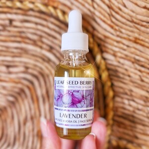 May include: A clear glass bottle with a white dropper top and a label that reads "Leaf Seed Berry Natural Effective Skin Care Lavender Infused Jojoba Oil | Face Serum".