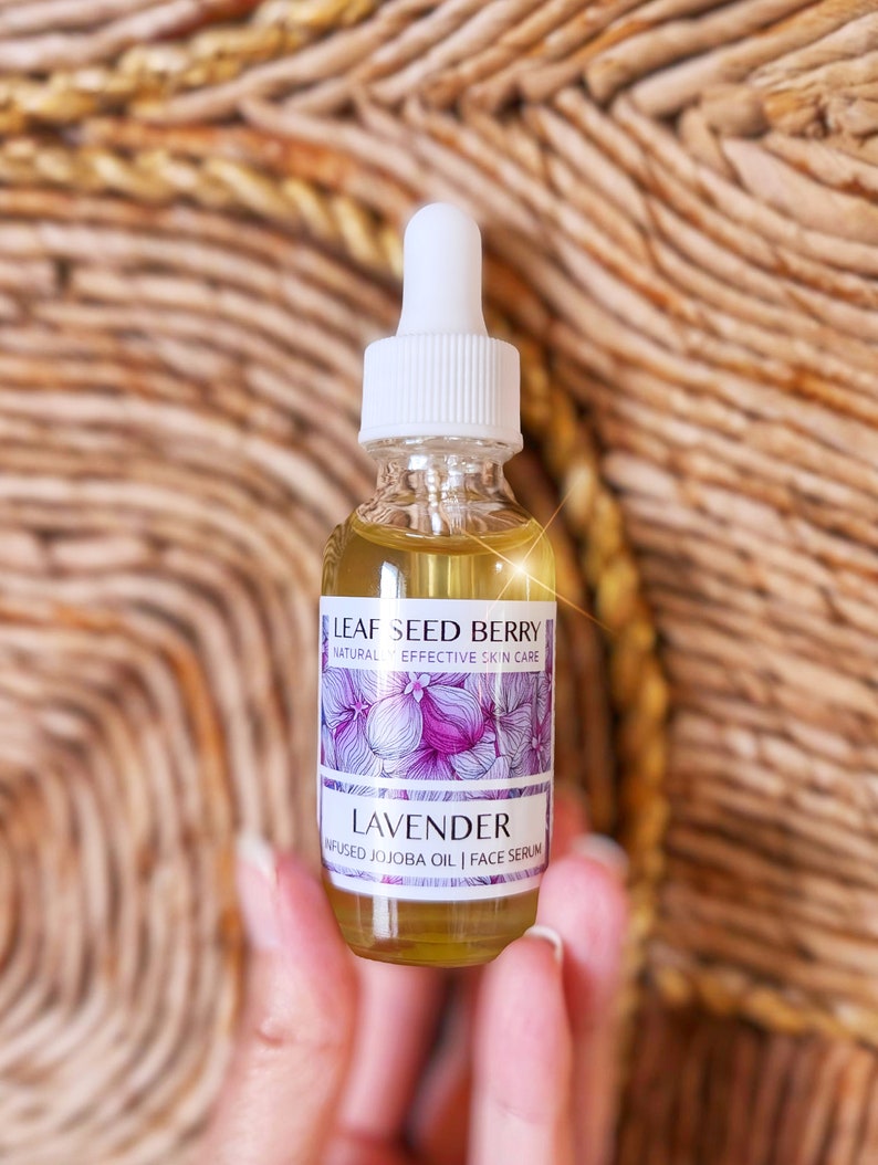 May include: A clear glass bottle with a white dropper top and a label that reads "Leaf Seed Berry Natural Effective Skin Care Lavender Infused Jojoba Oil | Face Serum".