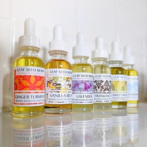 May include: Eight small glass bottles with dropper tops filled with a clear yellow liquid. Each bottle has a label with a different floral design and the text "Leaf Seed Berry" and "Naturally Effective Skin Care". The labels also list the scent of each bottle, including Ginger Turmeric, Vanilla Bean, Lavender, Frankincense, Sweet Meadow, and Chamomile.