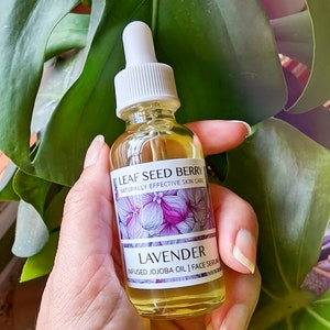 May include: A glass bottle of lavender infused jojoba oil face serum. The bottle is labeled "Leaf Seed Berry Naturally Effective Skin Care" and "Lavender Infused Jojoba Oil | Face Serum".