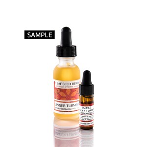 May include: Two glass bottles with droppers, one larger and one smaller. Both bottles contain a yellow liquid and have labels with the text "Leaf Seed Berry Naturally Effective Skin Care" and "Ginger Turmeric Infused Jojoba Oil | Face Serum". The smaller bottle has a label that says "Sample Ginger + Turmeric Infused Jojoba Oil".