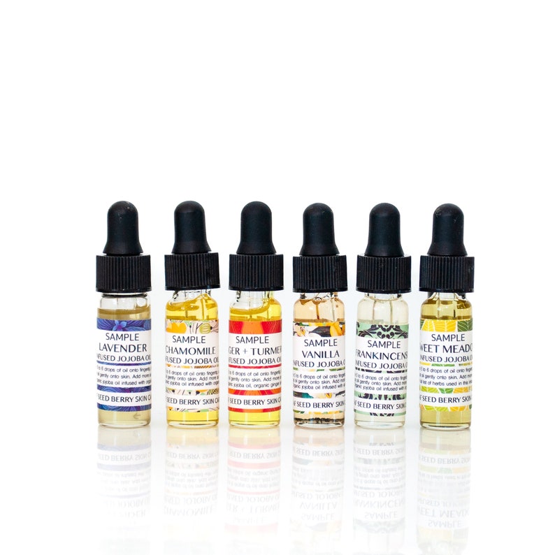 May include: Six small glass bottles with dropper tops, each containing a different essential oil blend. The bottles are labeled with the names of the blends: Lavender, Chamomile, Ginger + Turmeric, Vanilla, Frankincense, and Sweet Mead. Each bottle is labeled "Sample Infused Jojoba Oil".