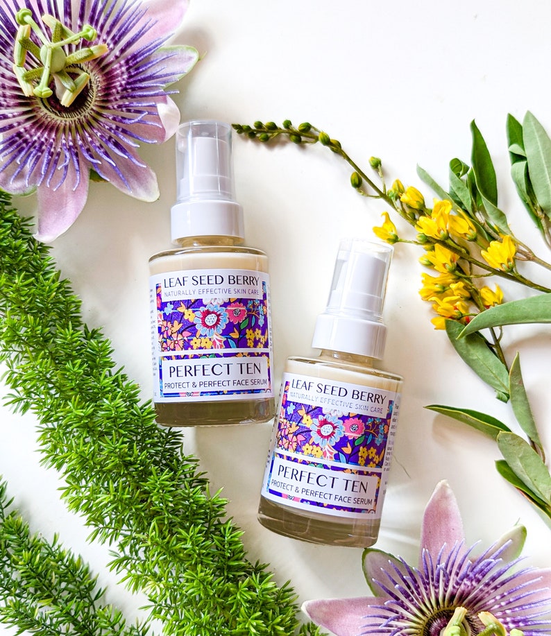 May include: Two glass bottles of face serum with a floral design. The bottles are labeled "Leaf Seed Berry Naturally Effective Skin Care Perfect Ten Protect & Perfect Face Serum".